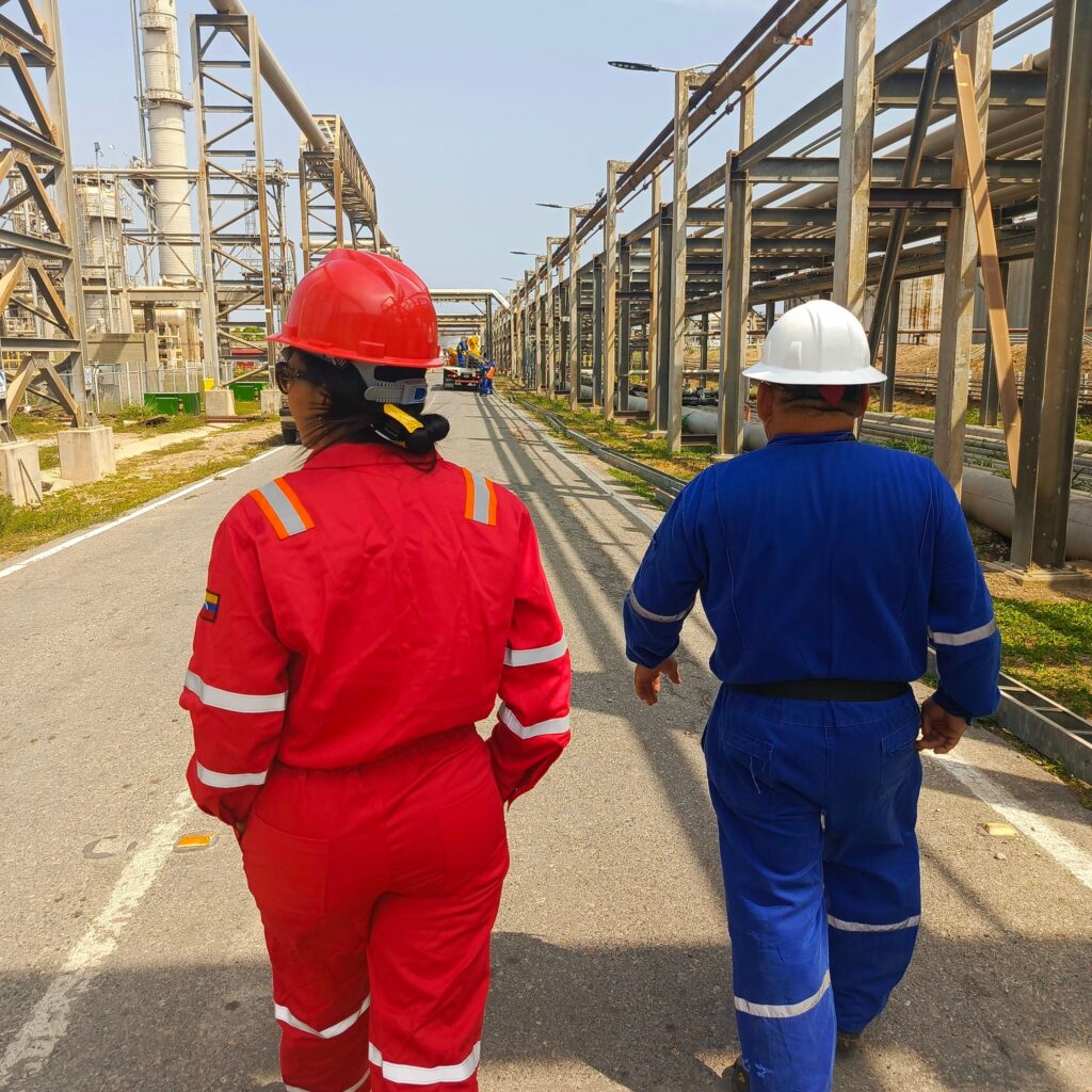 Two workers in protective gear walk through an industrial plant, ensuring safety compliance.